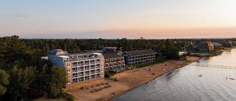 A coastal hotel with multiple buildings, a beach, and a river.