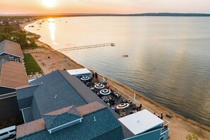A waterfront hotel with outdoor seating and a pier extending into the water.