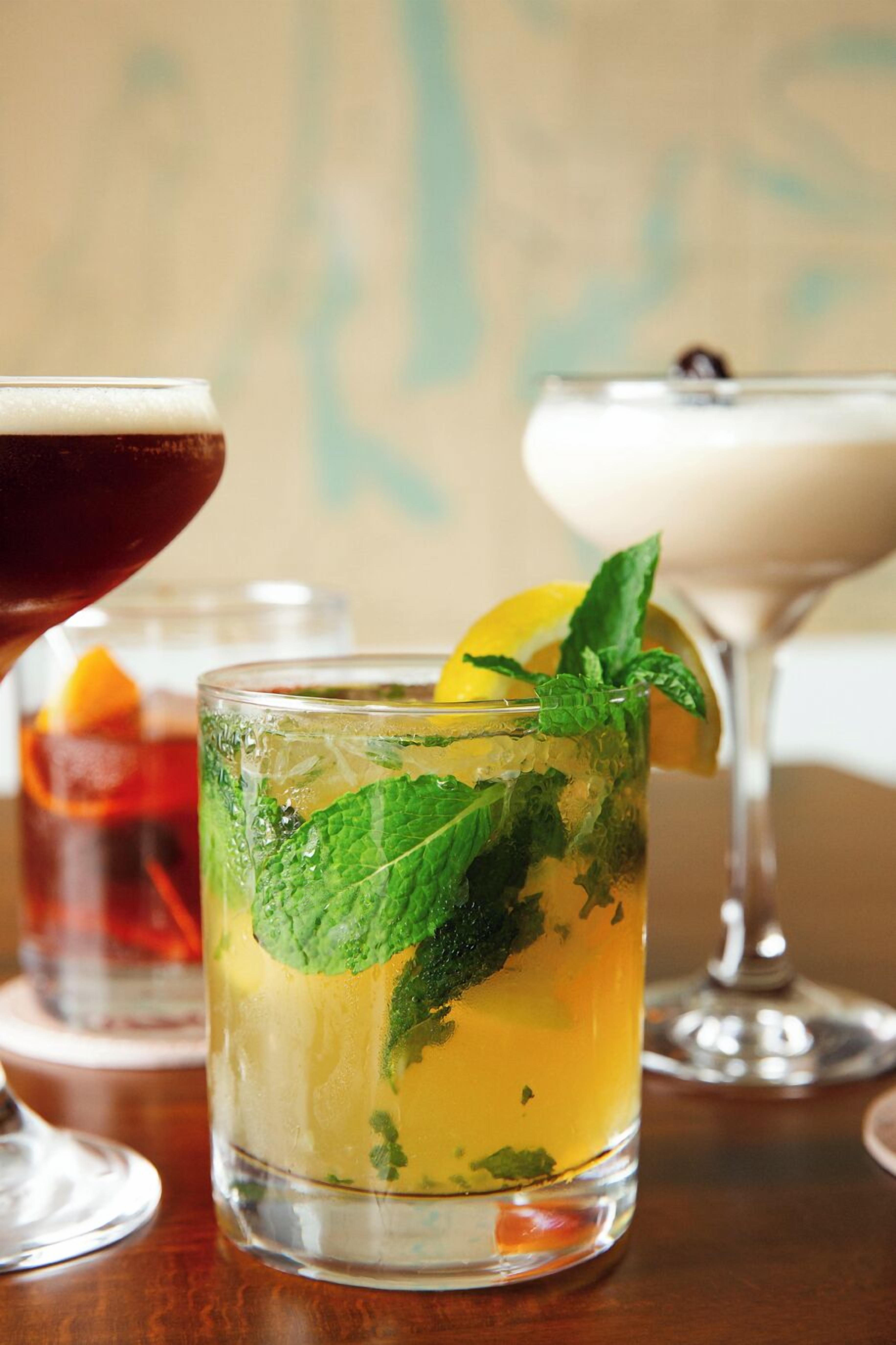 A glass of iced tea with mint leaves and a lemon slice.