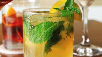 A glass of iced tea with mint leaves and a lemon slice.