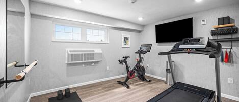 A home gym with a treadmill, stationary bike, and exercise equipment.