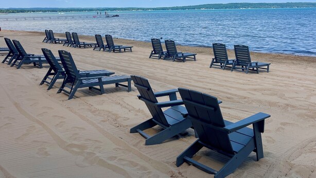 A beach with rows of lounge chairs and a clear view of the ocean. - Alexandra Inn (Traverse City)