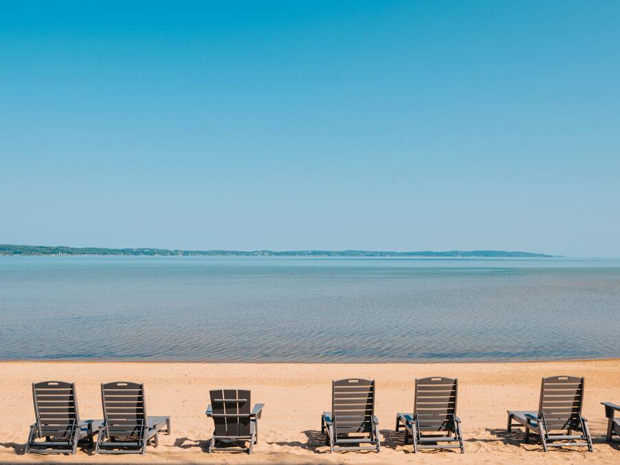 Una spiaggia con file di sdraio di legno rivolte verso l'oceano.