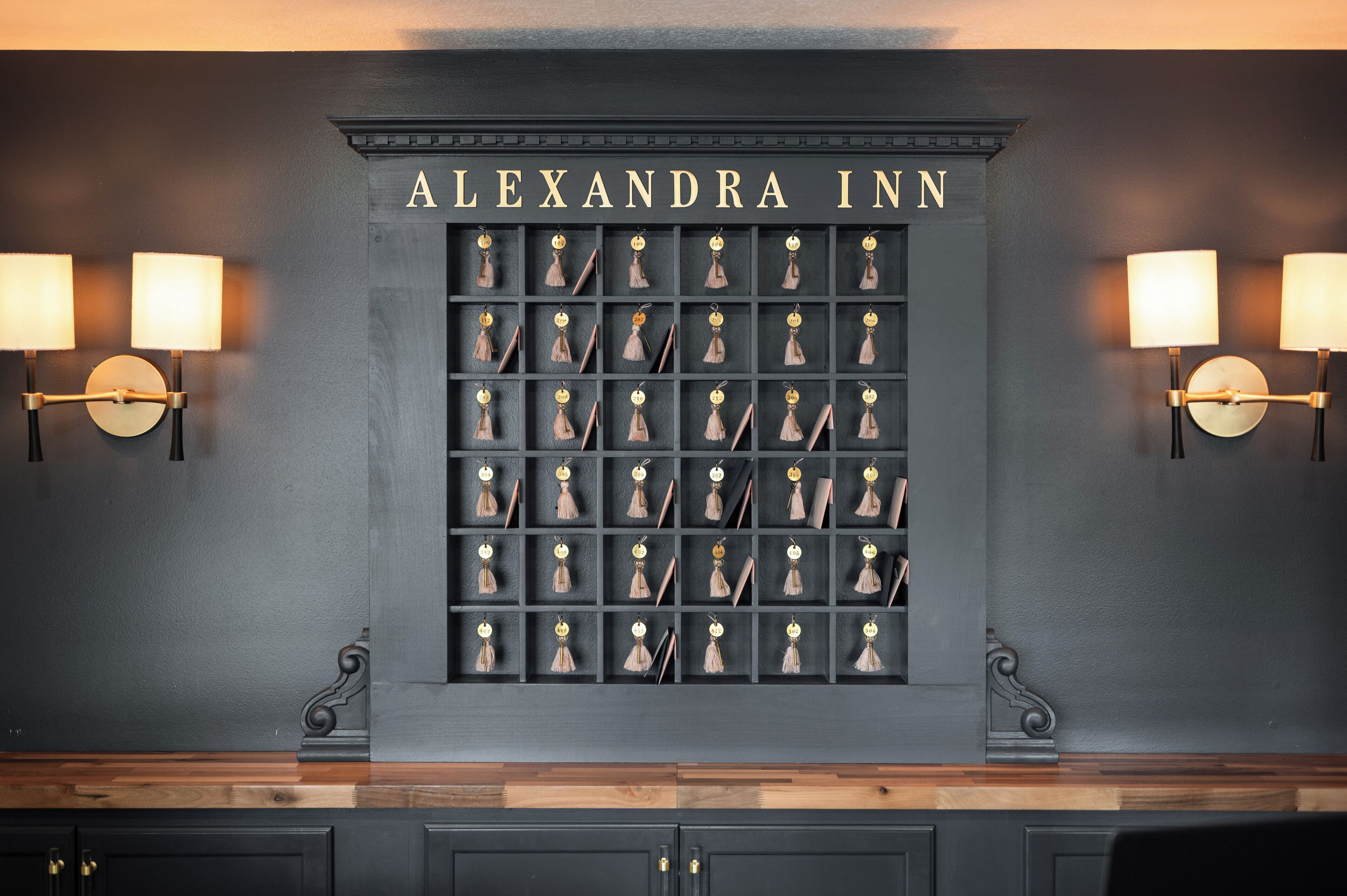 Un mur orné d’une grille de pompons suspendus, sur laquelle on peut lire l’inscription « ALEXANDRA INN ».