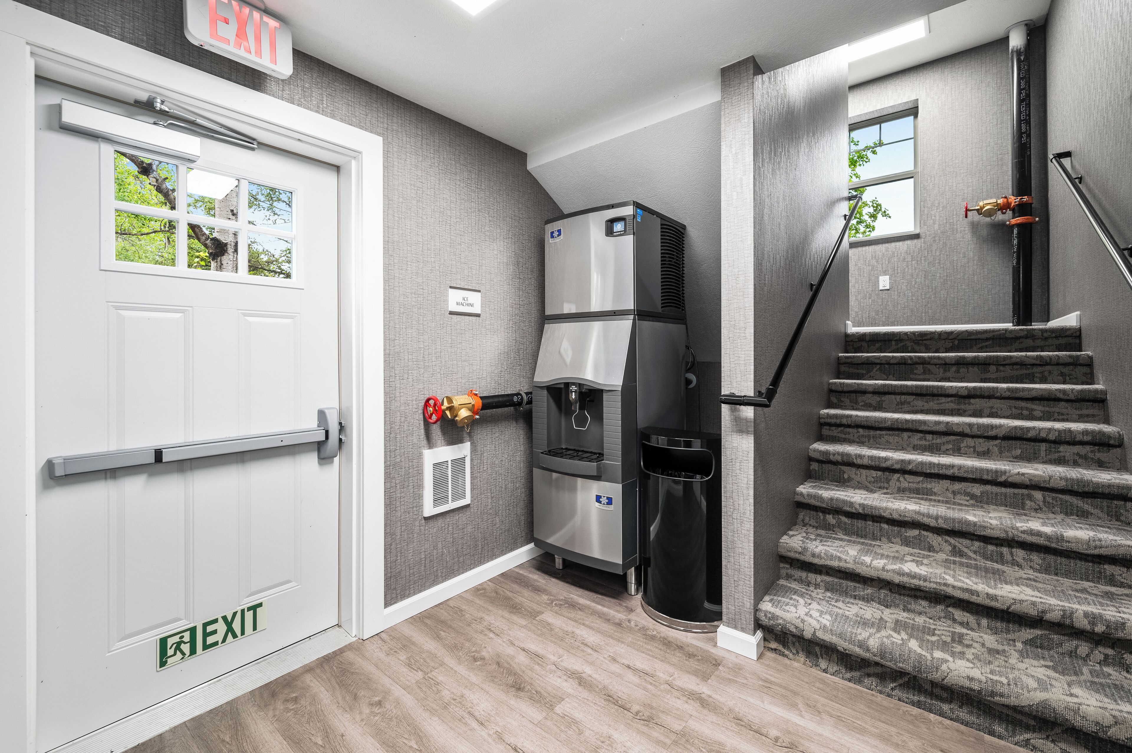 A hotel entrance with an exit sign, a water dispenser, and a staircase.