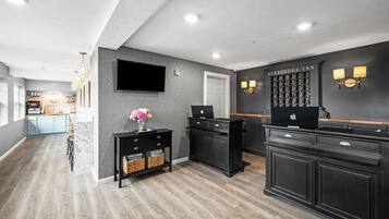 A modern kitchen with dark cabinetry, a flat-screen TV, and a wine rack.