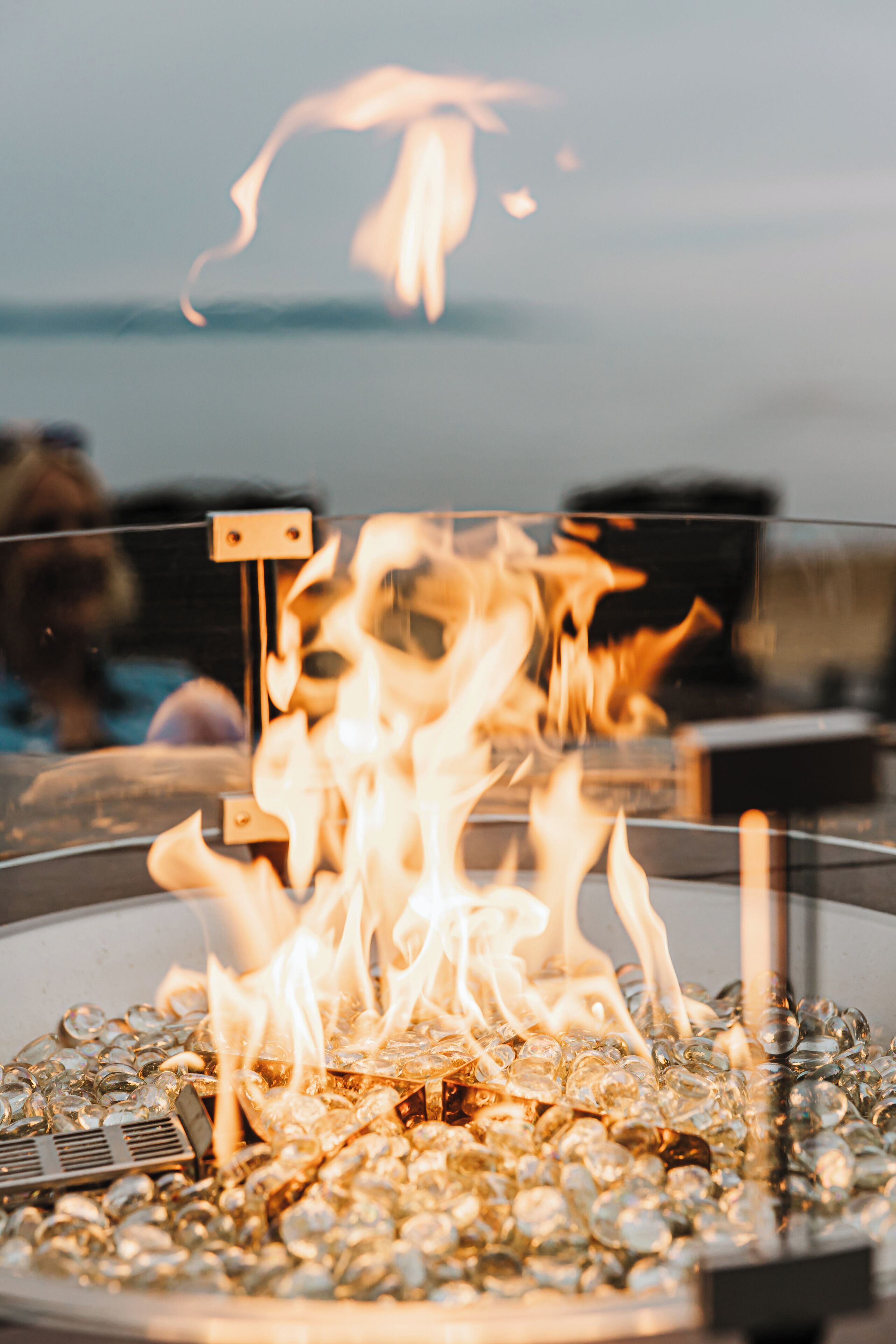 Ein gläsernes Gehäuse mit Feuer darin, umgeben von Glassteinen.