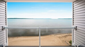 A balcony with a view of a calm lake and a sandy beach. - Alexandra Inn (Traverse City)