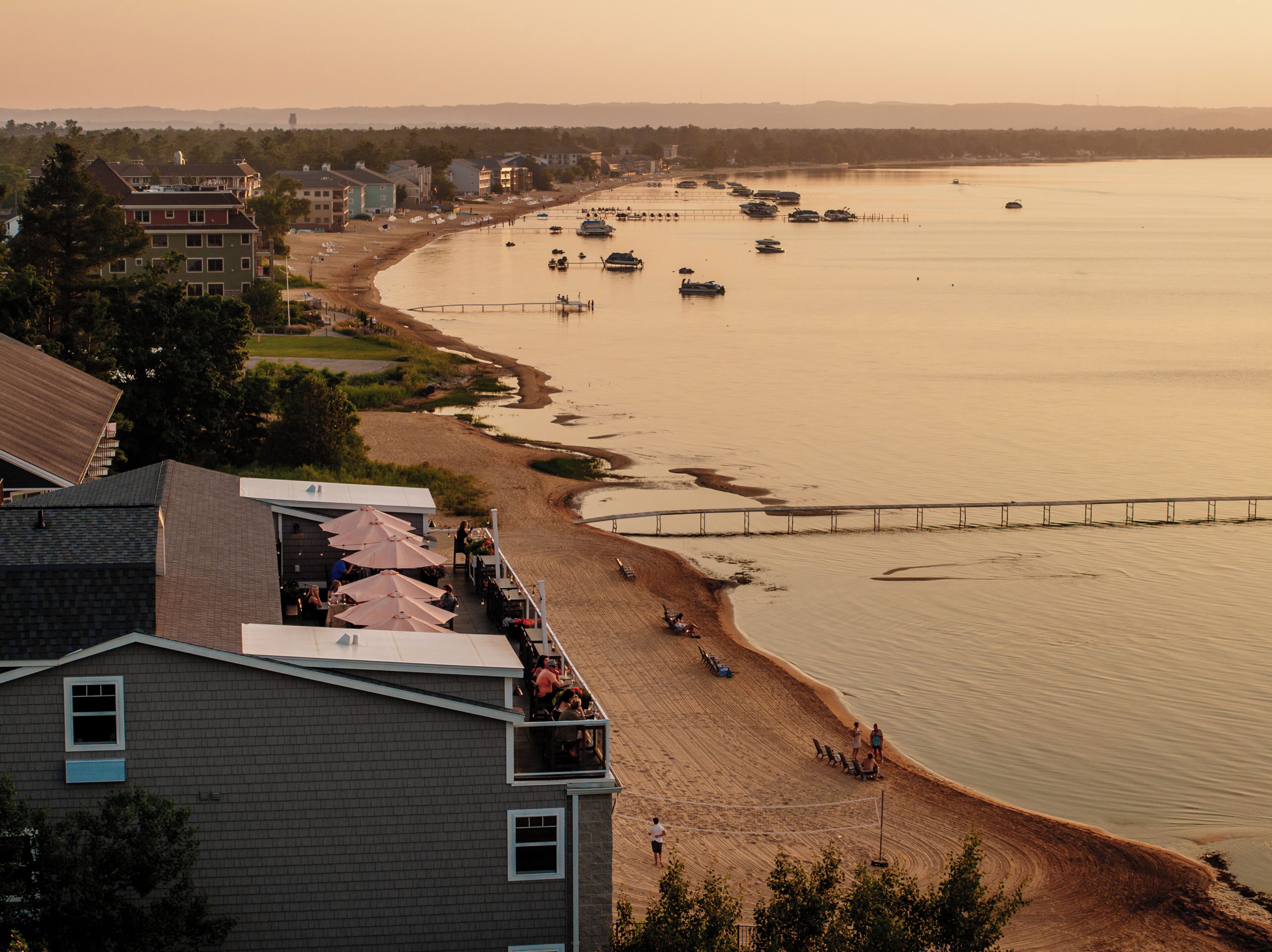 Vista costeira com praia, um cais e barcos.
