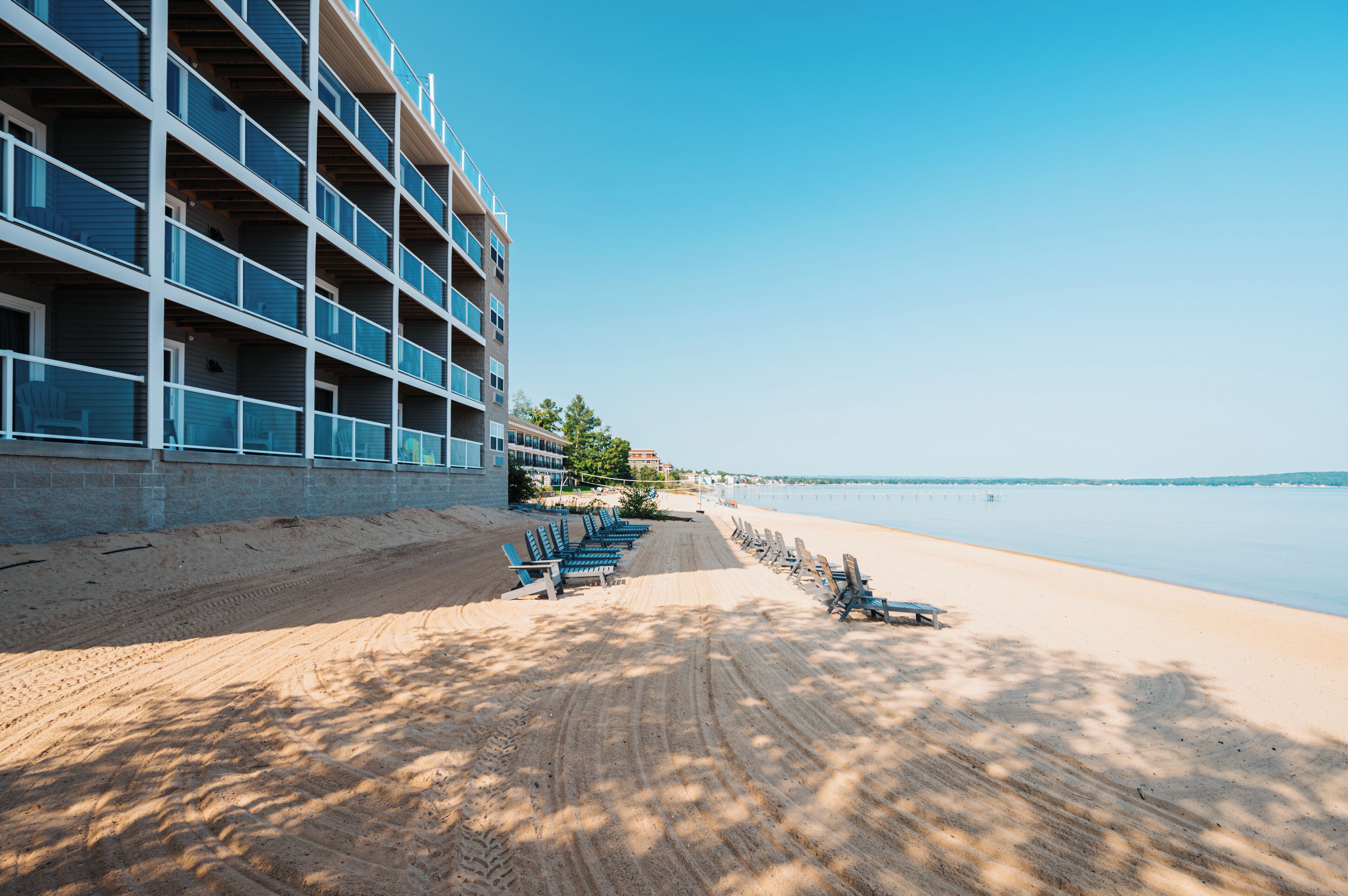 A beachfront hotel with multiple balconies, a sandy beach, and a clear view of the sea.