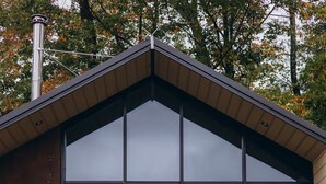A modern building with a large glass facade, numbered '5', and a fire pit in front. - Lakefront cabin #5 / Leisure Lake Resort (Pocono Township)