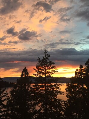A sunset over a lake with trees in the foreground.