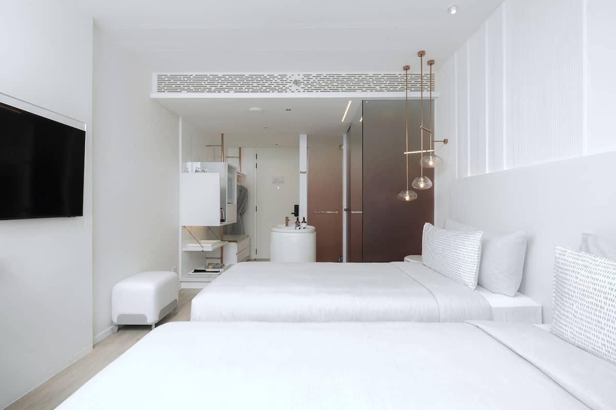 A modern bedroom with a large bed, a bedside table, a wardrobe, and a TV mounted on the wall.