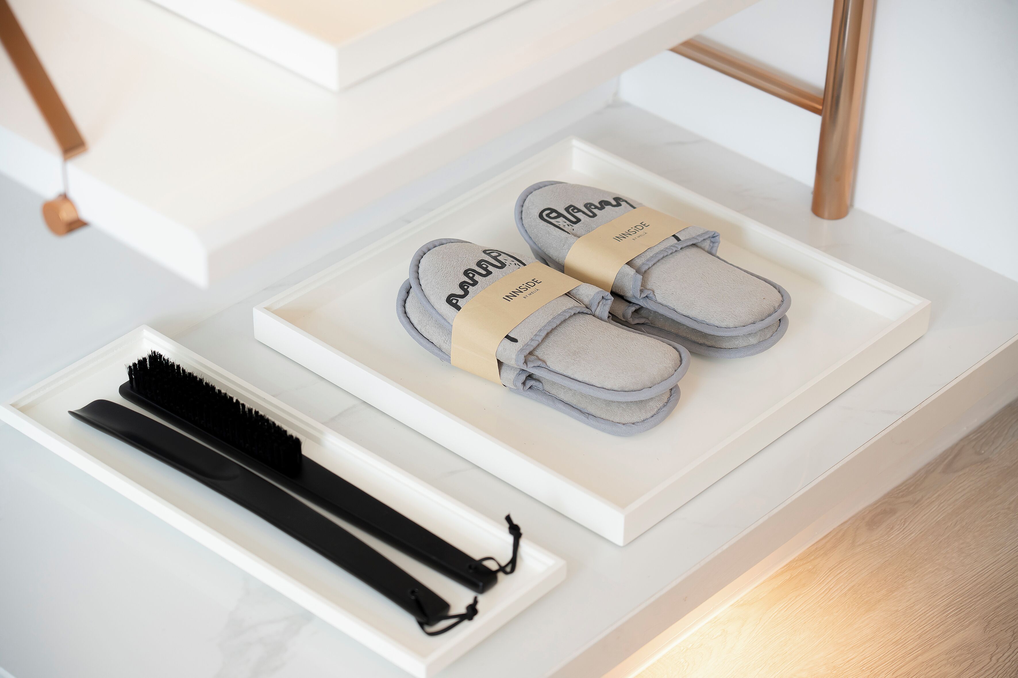 A neatly organized drawer with a pair of grey slippers, a black hairbrush, and a beige towel.