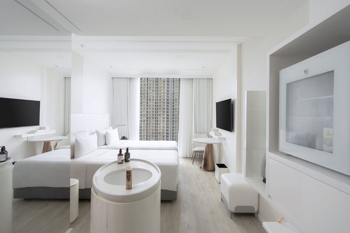 Ett modernt hotellrum med en stor säng, en sittgrupp, en TV och utsikt över stadsbilden.