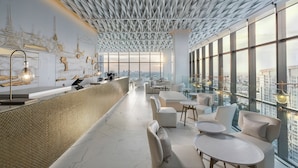 A modern bar area with a high ceiling, large windows, and a view of the cityscape. - INNSiDE by Meliá Bangkok Sukhumvit (Bangkok)