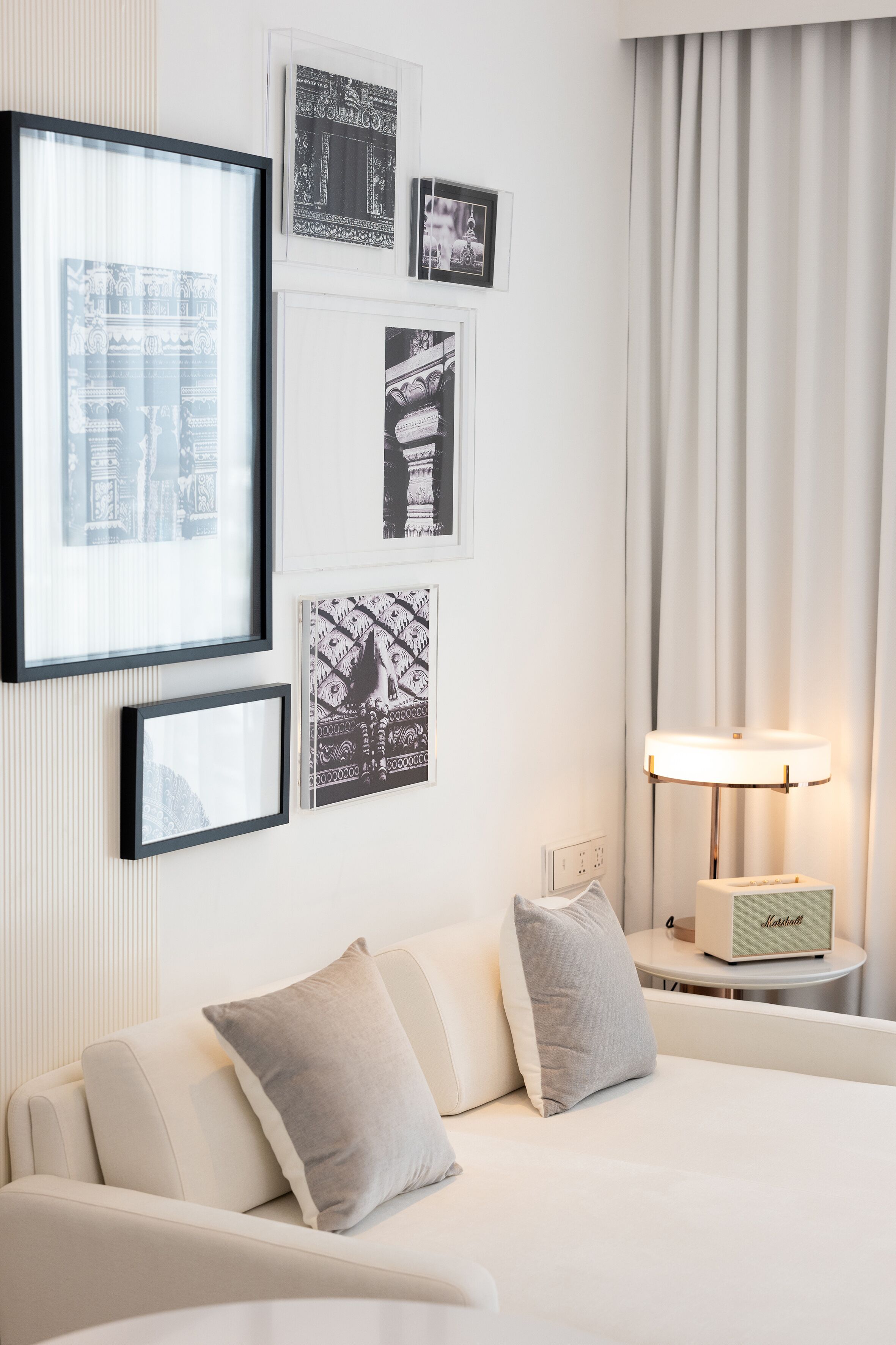 A hotel room with a bed, a bedside table with a lamp, and framed pictures on the wall.
