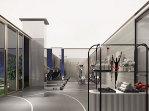 A modern gym with exercise equipment, a reception area, and large windows.