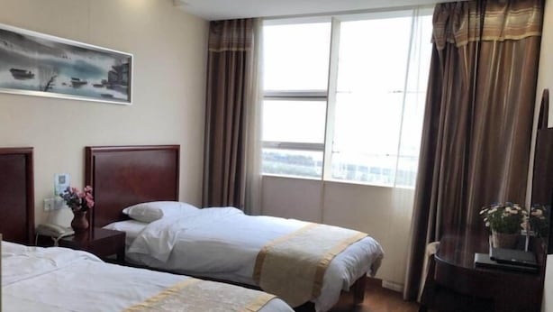 A hotel room with two beds, a desk, a chair, a window with curtains, and a painting on the wall. - Greentree Inn Wuxi New District High Speed Rail Station Newland Family Express Hotel (Wuxi)