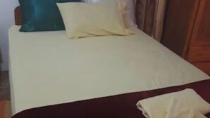 A bed with a white sheet and a red blanket, a teal pillow, and a yellow pillow. - 1 Bedroom with 1 twin bed and full bathroom.. (Scarborough)