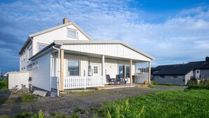 Een huis met twee verdiepingen, een overdekte veranda en een klein raam.