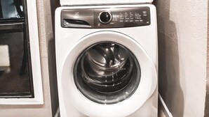 Een gestapelde wasmachine en droger staan in een hoek van de ruimte.