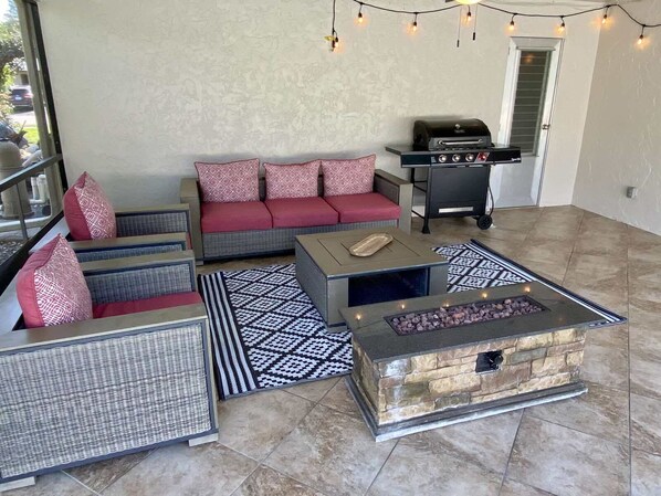 A cozy outdoor seating area with a stone fire feature, a grill, and string lights. - House with private pool (Naples)