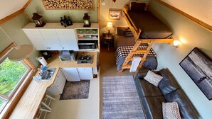 Una cabaña compacta y bien organizada con kitchenette, una zona de estar acogedora y una cama en altillo.