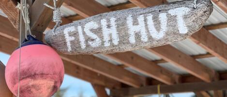 Une pancarte en bois portant l’inscription « CABANE À POISSON » est suspendue à une structure.