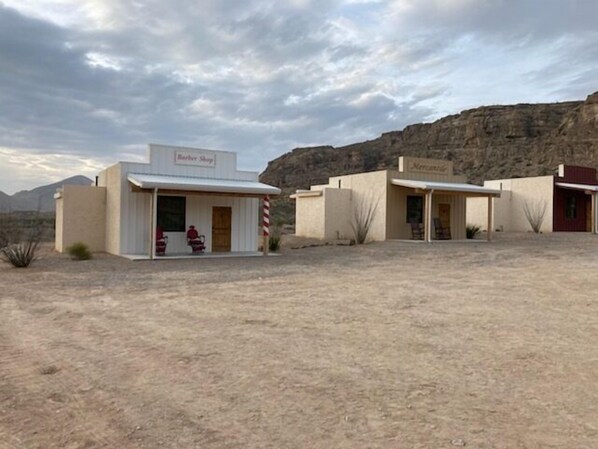 Woestijnlandschap met drie gebouwen, voorzien van de aanduidingen 'Barber Shop', 'Mercury' en 'Mercury'.
