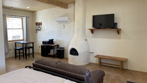 Une chambre à coucher comprenant un lit, une cheminée en pierre, un téléviseur, un bureau avec un ordinateur et une fenêtre.