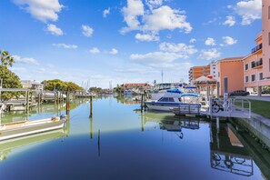 Un port de plaisance avec des bateaux amarrés, un ciel dégagé et des bâtiments en arrière-plan.