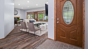 A modern living room with a wooden door, a sofa set, and a dining area. - Wine Country Escape - Hot Tub - Sleeps 12 (Geneva)