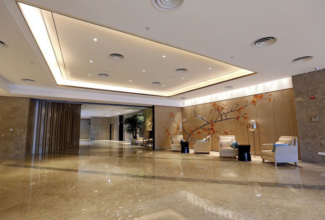 Um hall moderno com piso de mármore polido, iluminação embutida e mobiliário contemporâneo.