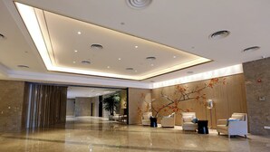 Un lobby moderno con piso de mármol pulido, iluminación empotrada y mobiliario contemporáneo.