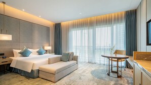 Een moderne hotelkamer met een groot bed, een bank, een kleine tafel en een televisie.