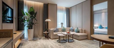 A modern hotel room with a sofa, coffee table, and a TV.