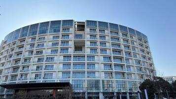 Un edificio moderno de varios pisos con fachada curva, ventanas grandes y un letrero al frente.