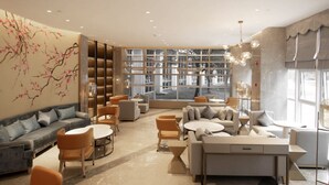 Een moderne zithoek met banken, fauteuils en een salontafel, met een groot raam en uitzicht op de straat.