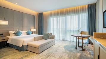 Una habitación de hotel moderna con una cama grande, un sofá, una mesita y un televisor.