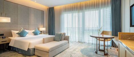 A modern hotel room with a large bed, a sofa, a small table, and a TV.