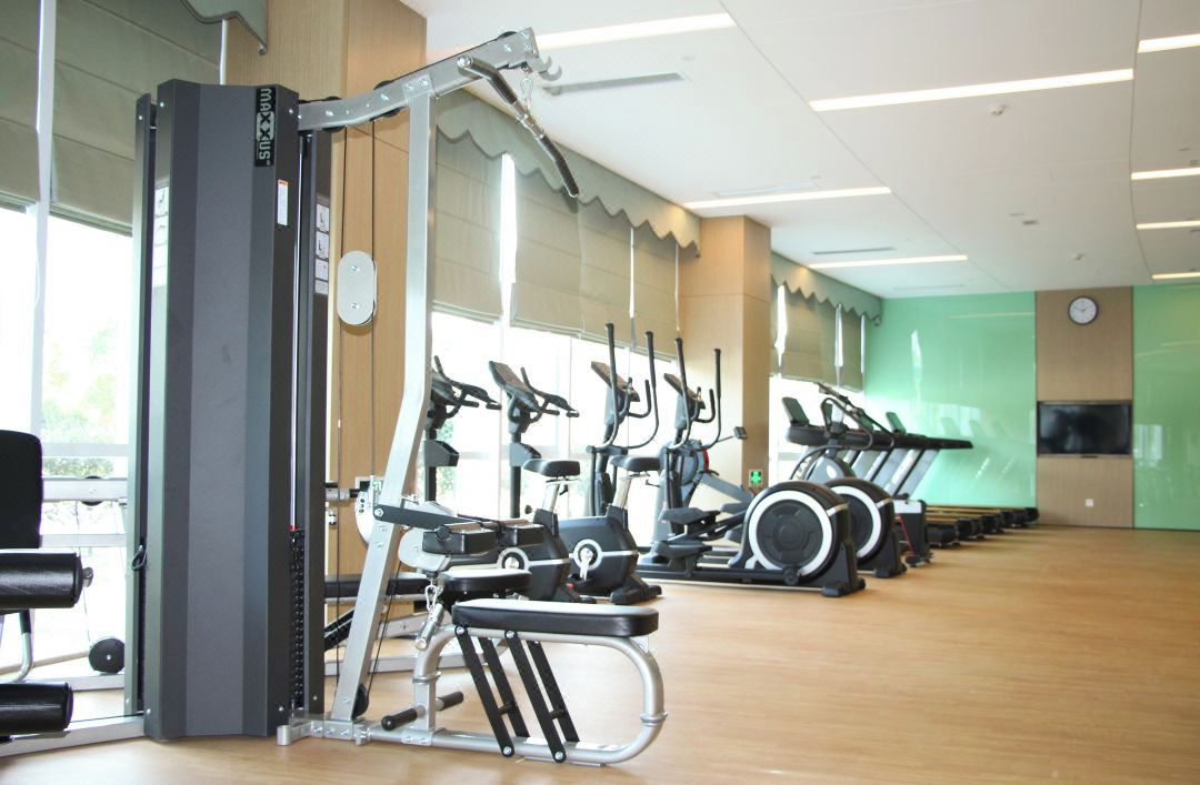 Un gimnasio con diversos equipos de ejercicio, incluyendo cintas de correr, bicicletas estáticas y máquinas de pesas.