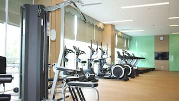 Un gimnasio con diversos equipos de ejercicio, incluyendo cintas de correr, bicicletas estáticas y máquinas de pesas.
