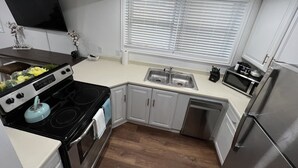 Una cocina moderna con gabinetes blancos, un refrigerador de acero inoxidable, un microondas y una estufa.