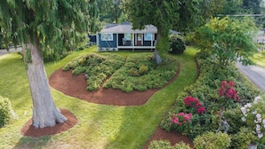 A house surrounded by a well-maintained garden with various shrubs and flowering plants. - Beachside Escape w/ Kayaks | Access to Seattle (Port Orchard)