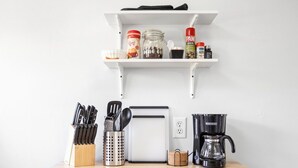 Eine Küche mit einer Holzausziehtischplatte, einer Kaffeemaschine, einem Toaster und verschiedenen Küchenutensilien.