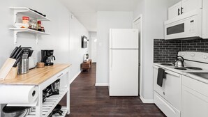Eine moderne Küche mit weißen Schränken, einer Holz Arbeitsplatte, einem eingebauten Kochfeld und einem Kühlschrank.