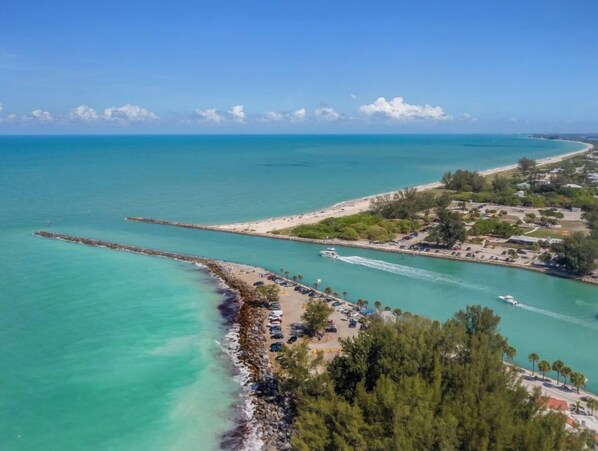 An aerial view of a coastal area with a beach, a pier, and a marina.