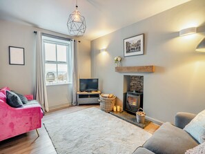 Ein Wohnzimmer mit Kamin, Fernseher, einem rosafarbenen Sofa und einem grauen Sofa.