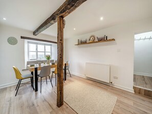 Ein Essbereich mit Holztisch, Stühlen, einem Fenster und einer Heizung.